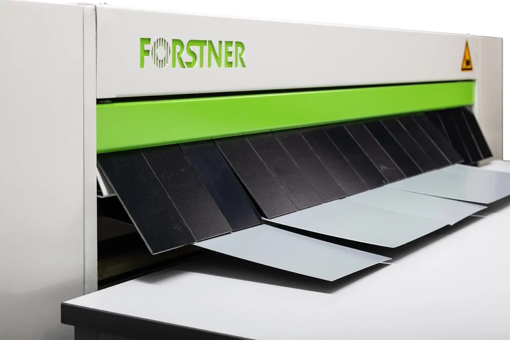 spaltad plåt matus ut på bord från klippsträcka forstner nuslit mot vit bakgrund