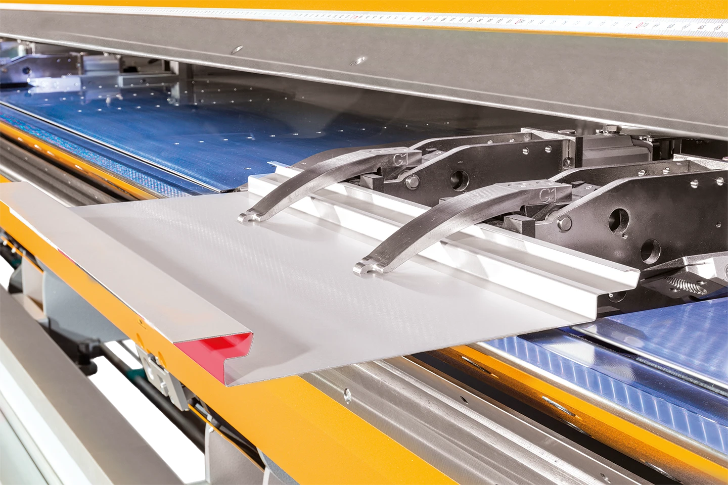 dubbla gripklor håller en plåt i en thalmann maskin mot vit bakgrund